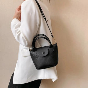 Sac seau minimaliste noir à texture litchi avec poignées rondes porté par un mannequin