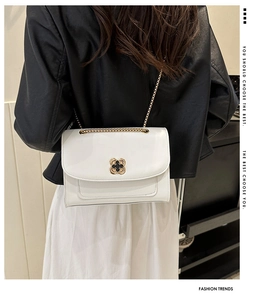Détail du sac blanc carré à chaîne avec boucle fleurie dorée et surpiqûres apparentes