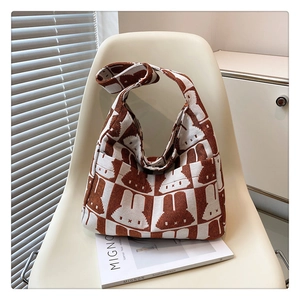 Detailed view of the brown rabbit checkerboard knit bag on a soft cream chair