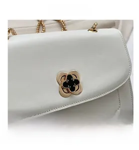 Détail du sac bandoulière en cuir blanc avec fermoir trèfle doré et chaîne chic