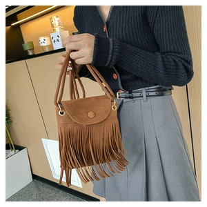 Gros plan d'un sac bandoulière en daim marron avec de longues franges et un rabat