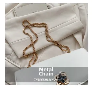 Détail de la sacoche en cuir blanc avec chaîne dorée et boucle tournante en trèfle