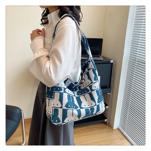 Detail of blue and white knitted tote bag with bunny pattern and wide shoulder strap