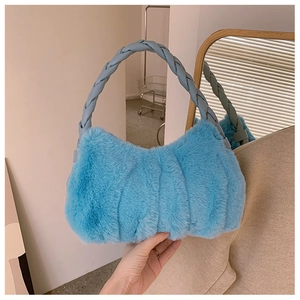 Détail du sac à main en fausse fourrure bleu clair avec anse en cuir tressé chic