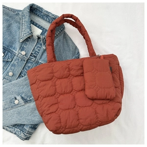 Detail view of brick red quilted tote bag with matching small organizer pouch