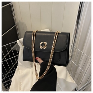 Détail d'un sac bandoulière en cuir noir avec fermoir doré en fleur et bandoulière chaîne