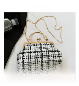 Detail of classic black and white tweed crossbody bag with gold metal handle and chain strap
