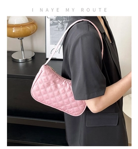 Detail of pink quilted underarm bag with glossy nylon texture and elegant stitching