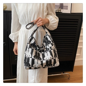Detail of knit hobo bag featuring black and white checkerboard rabbit pattern in daily use