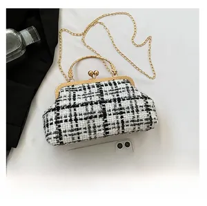 Detailed top view of a houndstooth tweed handbag with gold metal clasp and chain