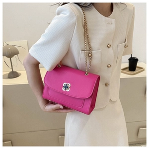 Détail d'un sac bandoulière rose fuchsia avec fermoir trèfle et fine chaîne dorée