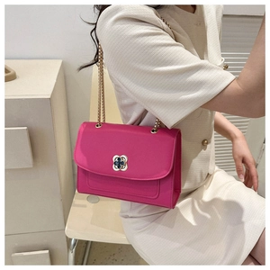 Détail d'un sac bandoulière rose rouge avec fermoir trèfle doré et bandoulière chaîne