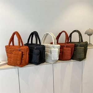 Quilted tote bags in five colors with matching mini pouches on a white minimalist shelf