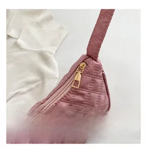 Detailed close-up of smooth golden metal zipper on pink quilted crossbody bag