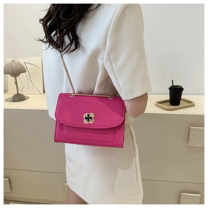 Détail d'un sac bandoulière rose avec fermoir fleur et chaîne dorée porté par mannequin