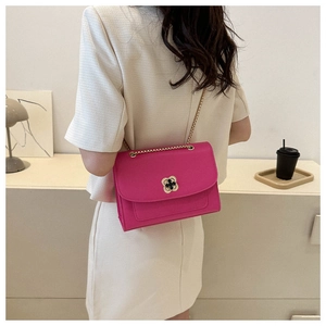 Détail d'un sac rose à chaîne avec fermoir floral doré et élégante bandoulière en métal