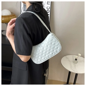 Detail view of mint green quilted rhombic pattern underarm bag on a model shoulder