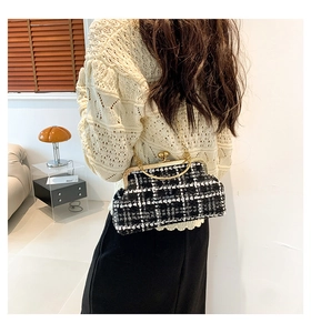 Close-up of black and white tweed handbag with golden sphere lock and metal handle