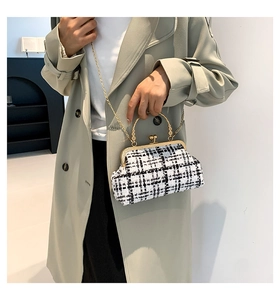 Close-up of elegant black and white plaid tweed handbag with golden sphere lock clasp