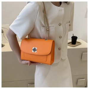 Détail d'un petit sac carré orange vif avec une boucle en métal en forme de trèfle
