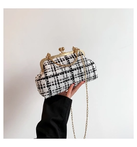 Detail of a vintage black and white tweed clutch bag with golden chain and metal clasp
