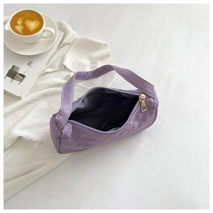 Detail view of the purple quilted underarm bag showing interior space and zipper
