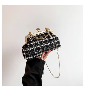 Detail of checkered tweed chain bag with gold metal clasp and top handle for women