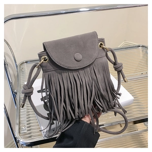 Détail d'un sac bandoulière gris en similicuir suédé avec de longues franges et rabat