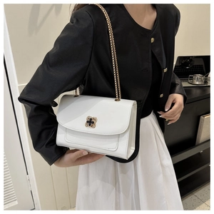 Gros plan d'un sac à bandoulière blanc avec fermoir pétale doré et bandoulière chaîne