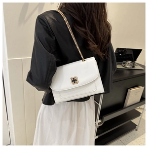 Détail du sac bandoulière en cuir blanc avec fermoir floral et chaîne dorée
