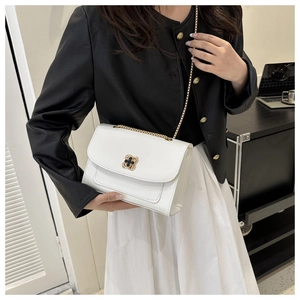 Détail d'un sac bandoulière blanc en cuir avec fermoir trèfle doré et bandoulière chaîne