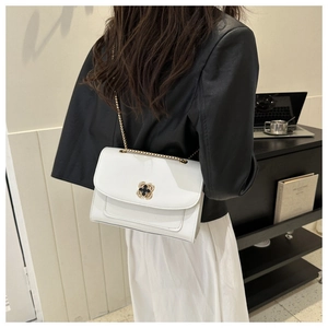 Gros plan sur le sac blanc élégant avec fermoir floral doré porté par un mannequin