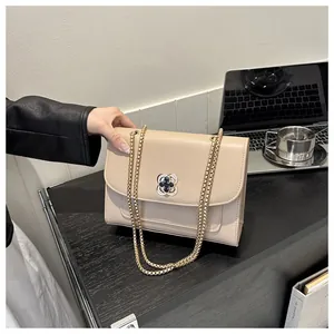 Gros plan sur sac bandoulière beige avec boucle trèfle et chaîne dorée chic
