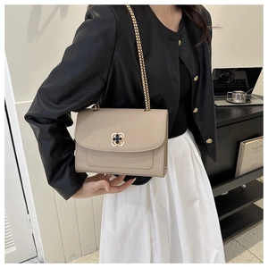 Détail du petit sac bandoulière beige avec chaîne dorée et boucle trèfle en métal