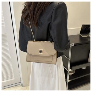 Sac bandoulière beige avec chaîne et fermoir floral porté par un mannequin de profil