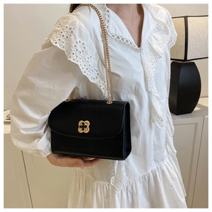 Détail du sac bandoulière en cuir noir avec boucle fleurie dorée et chaîne élégante