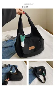 Détail d'un sac cabas en toile noire avec étiquette en cuir et pendentif peluche