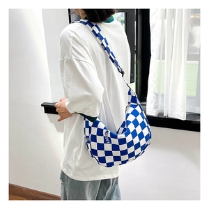 Détail du sac bandoulière à damier bleu avec imprimé mode et texture en toile de forme demi-lune