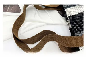 Detail of the thick brown canvas strap and textured striped weave on a large tote bag