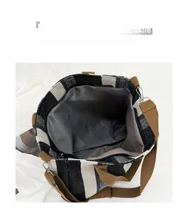 Detail view of large canvas tote bag with black stripes and brown woven shoulder strap