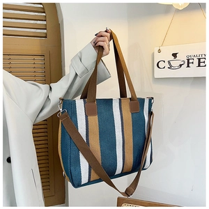 Detail of large canvas tote with teal and caramel vertical stripes and woven handles