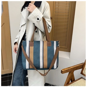 Close-up of woven tote bag with vertical stripes in teal, white and brown tones