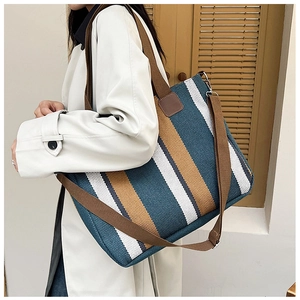 Detail showing blue and yellow striped canvas tote bag with brown leather reinforcement