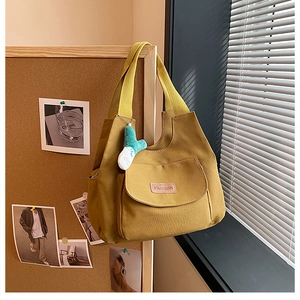 Détail du sac fourre-tout en toile jaune avec poche à rabat et pendentif peluche