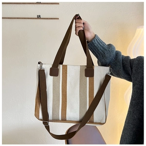Detailed view of canvas tote bag with brown vertical stripes and silver metal hardware