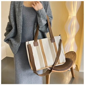 Detail of canvas tote bag showing brown stripes and adjustable shoulder strap texture