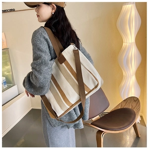 Detailed view of beige canvas tote bag with brown stripes and matching wide shoulder strap