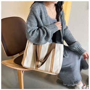 Detailed view of canvas tote bag with brown plaid stripes resting on a leather chair