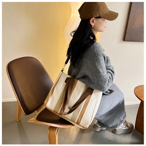 Lifestyle shot showing a large canvas tote bag with brown stripes on a model