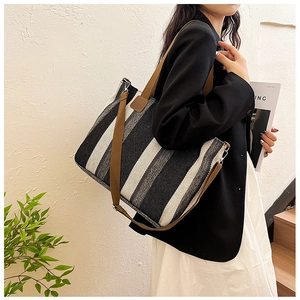 Detail of a large checkered canvas tote bag with brown straps in a lifestyle setting